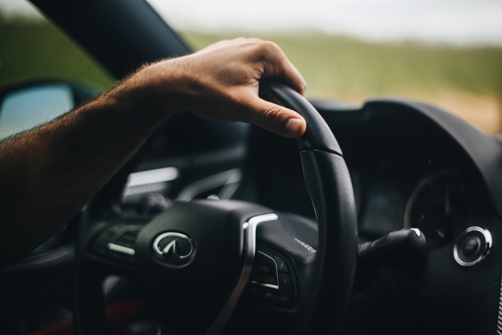 person holding black bmw steering wheel