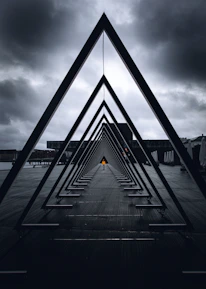 black metal bridge on sea under gray clouds