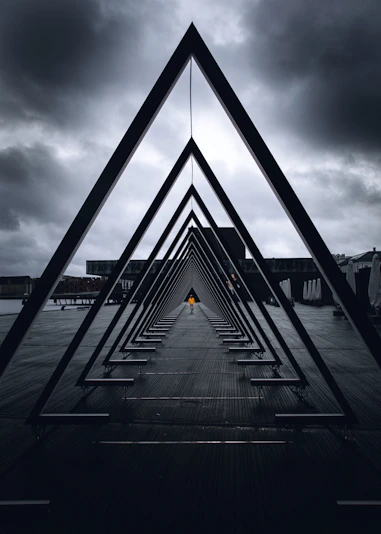 black metal bridge on sea under gray clouds