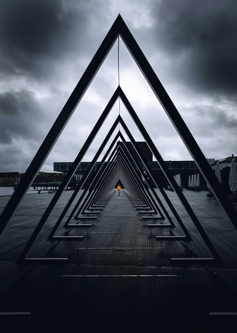 black metal bridge on sea under gray clouds