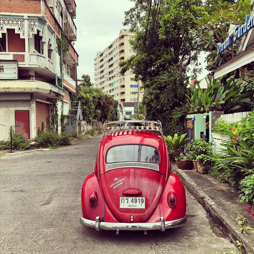 red volkswagen beetle parked on roadside near buildings during daytime
