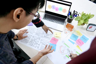 man designing wireframes at desk with laptop