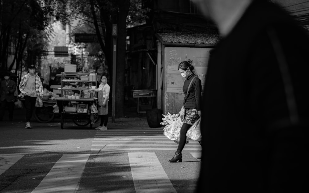 grayscale photo of woman in wedding dress walking on sidewalk