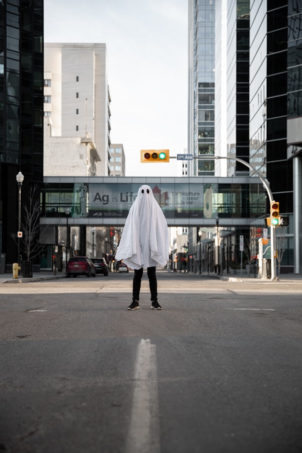 A person wearing a sheet that looks like a ghost standing in an empty street