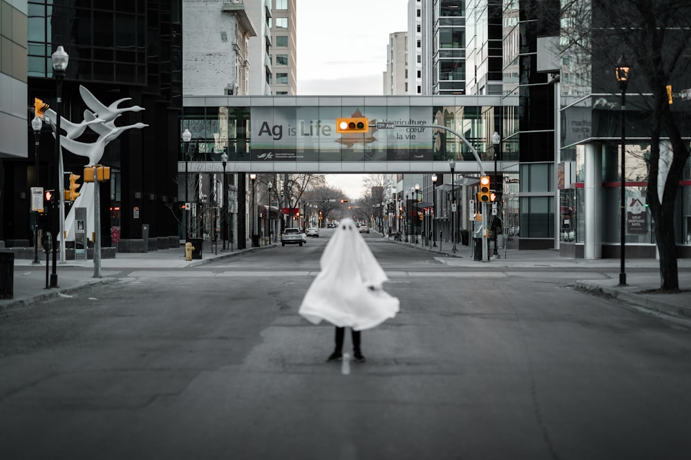 femme en robe blanche marchant sur la voie piétonne pendant la journée