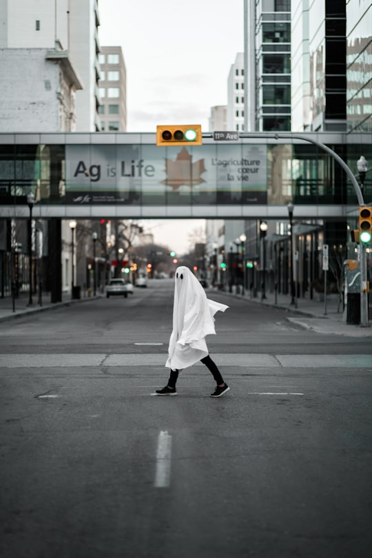 person in white robe walking on sidewalk during daytime in Regina Canada