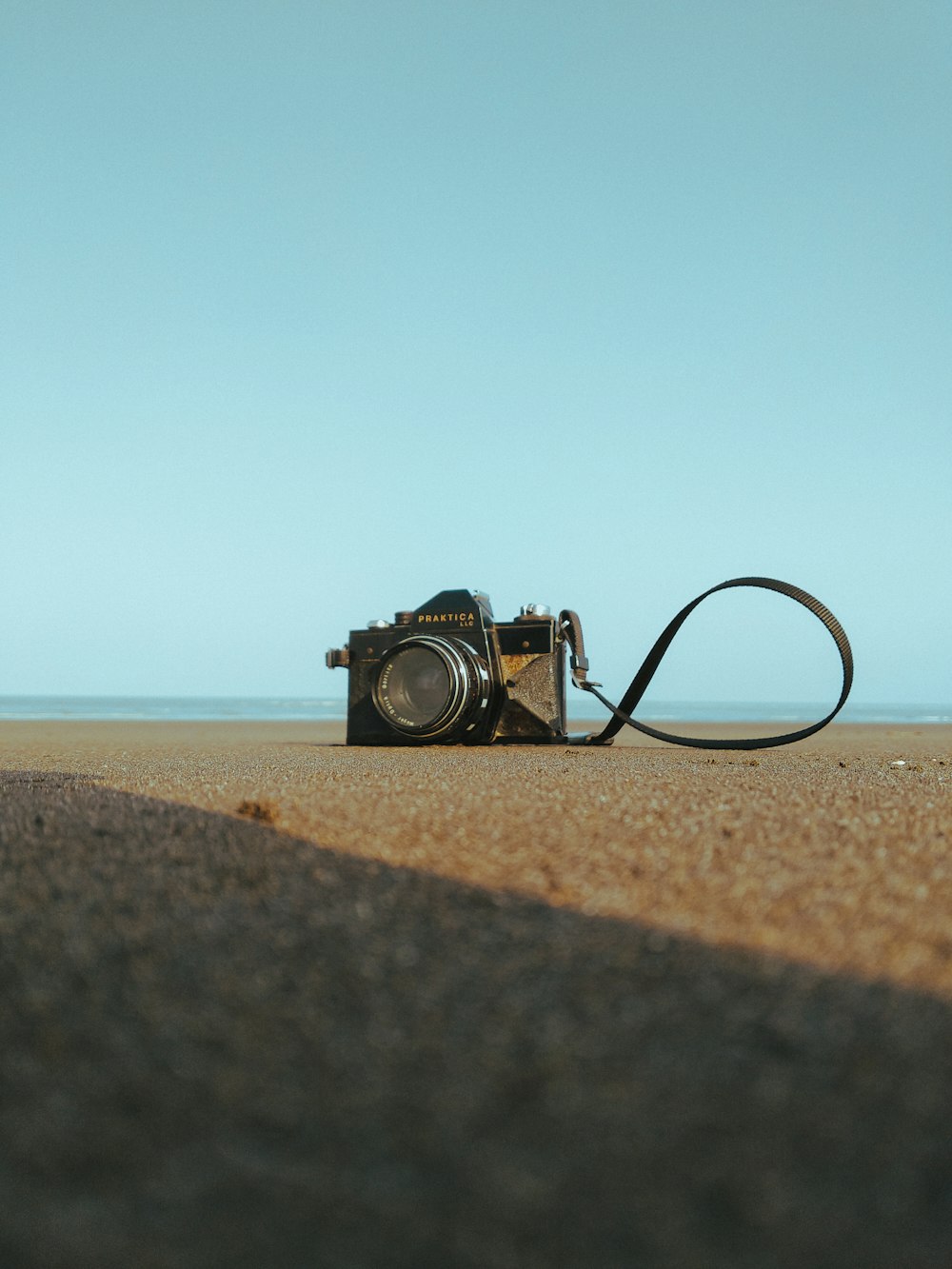 black and silver dslr camera on brown sand