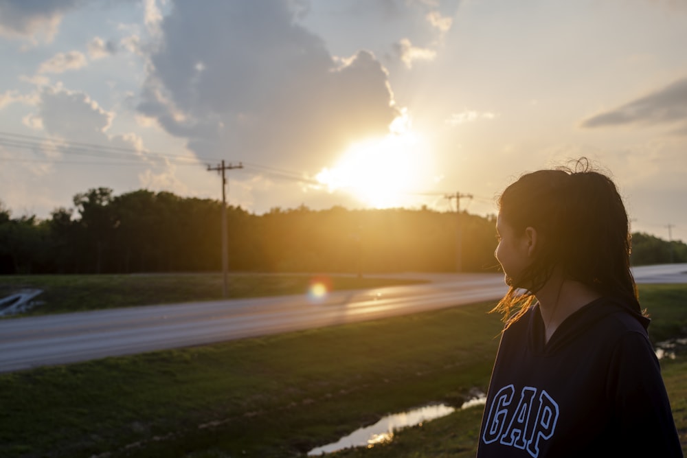 man in blue and white hoodie standing on road during sunset