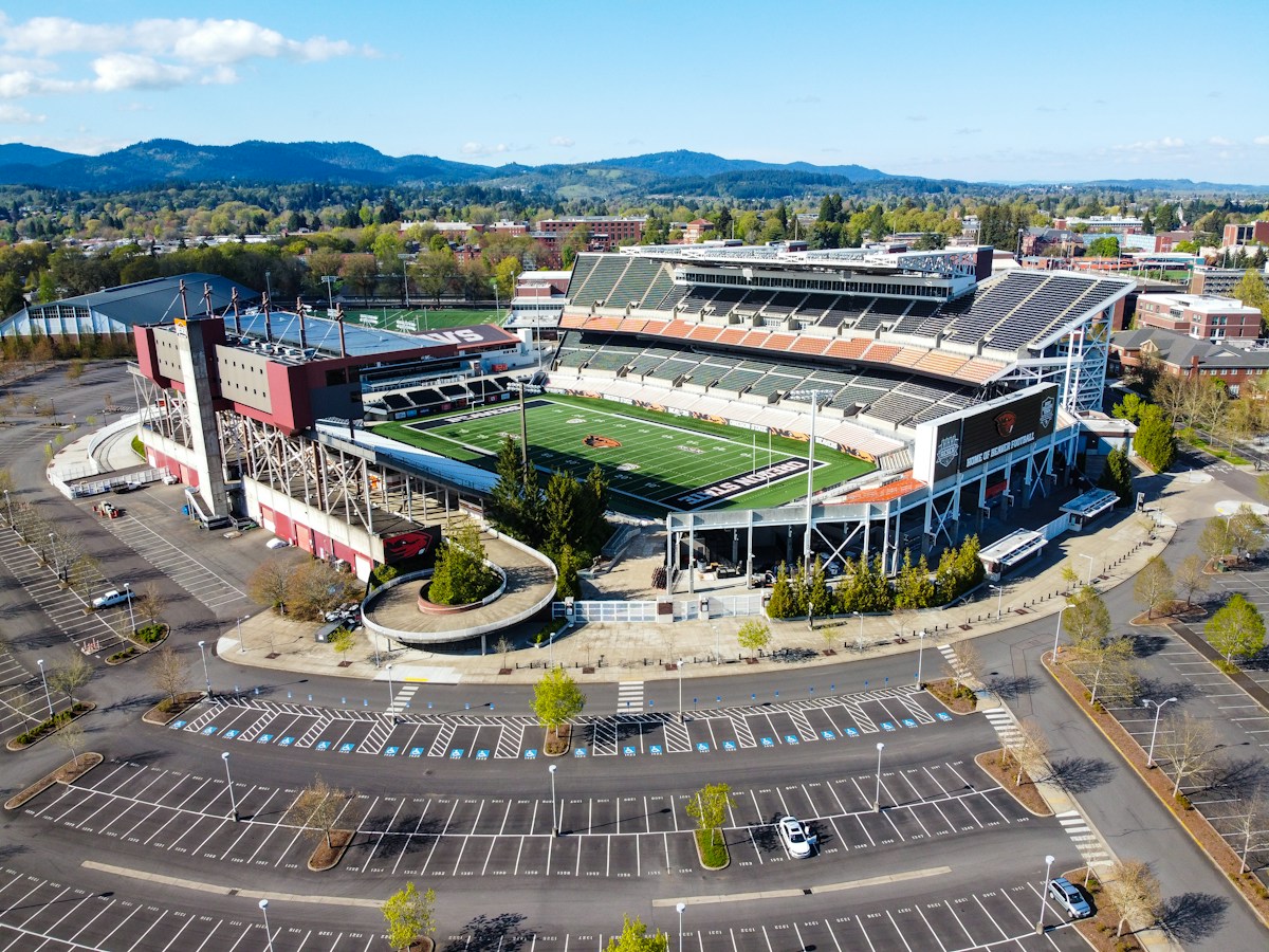 Aerial view of a crowded parking lot with cars, tents, and people setting up for a tailgate party.