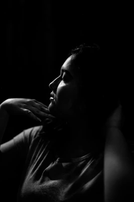 An elegant black and white portrait of a person dressed for a formal event, with a hint of gold light highlighting their wrist where perfume is applied.