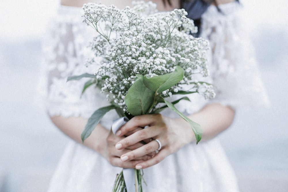 person holding white flower bouquet