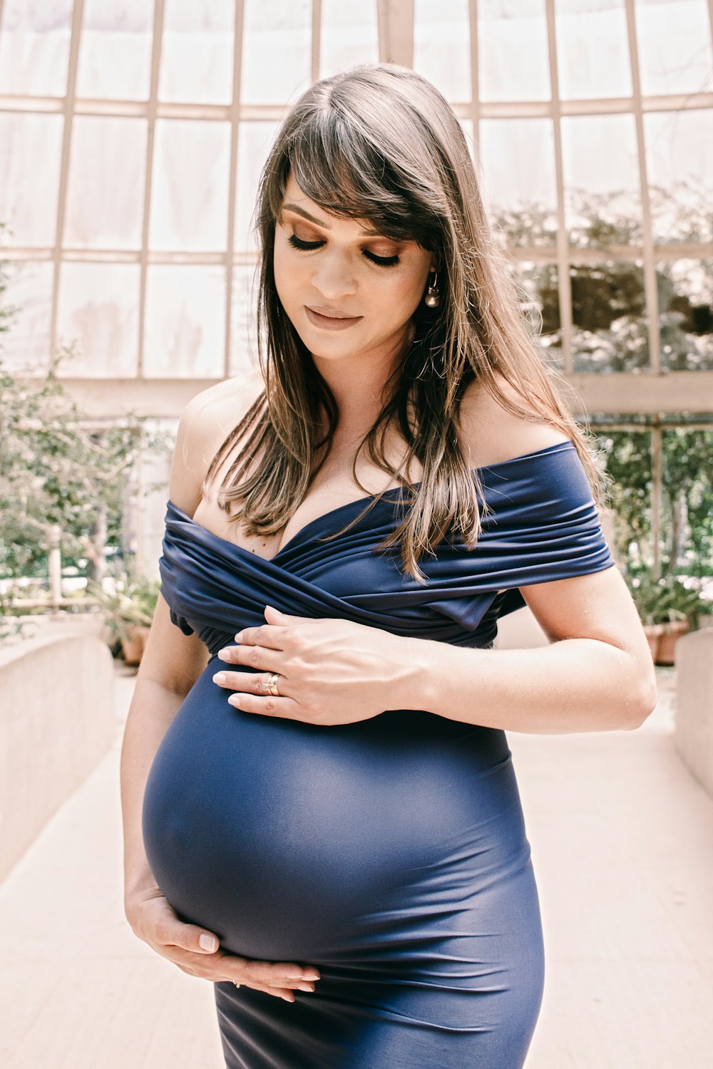 woman in blue and white stripe tank top and blue denim jeans sitting on white concrete