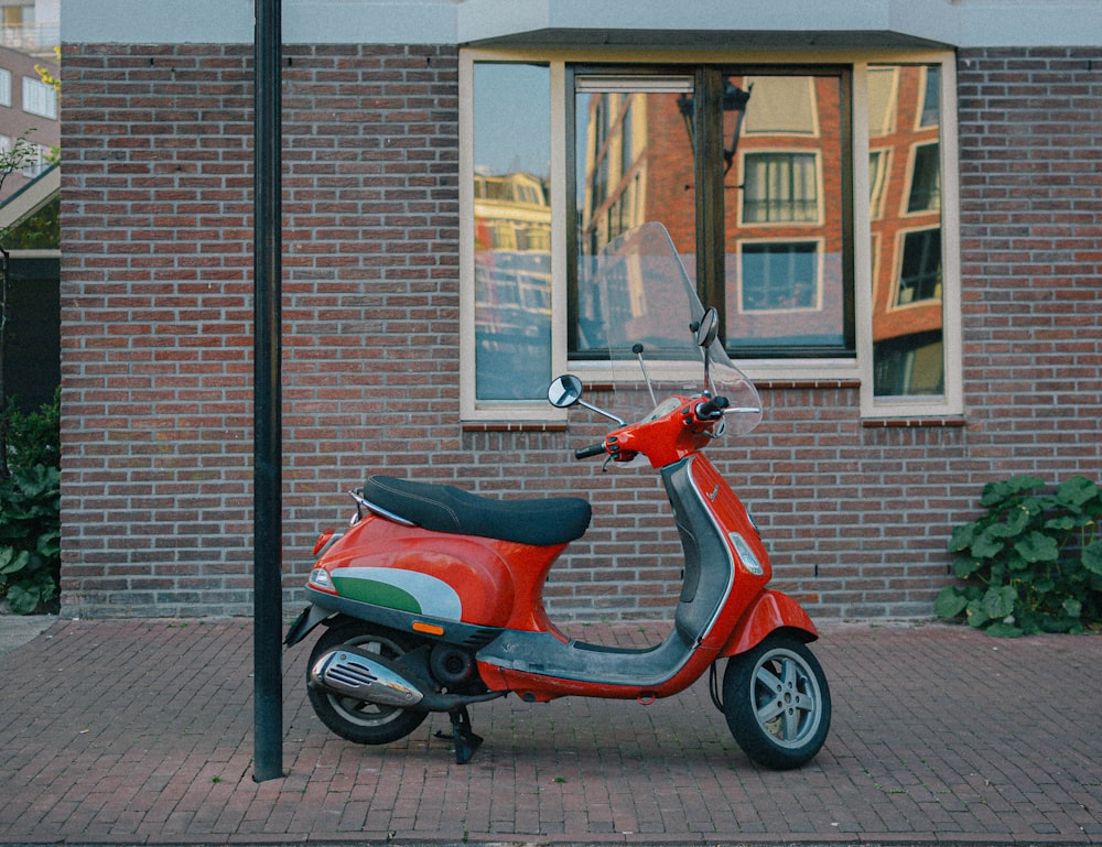 red and black motor scooter parked beside brown brick building