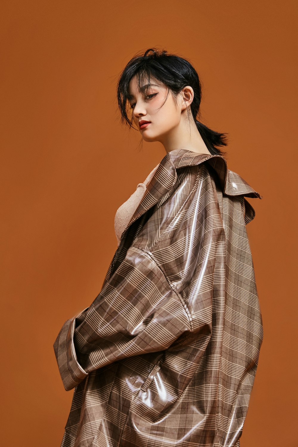 a woman in a brown jacket standing against a brown background