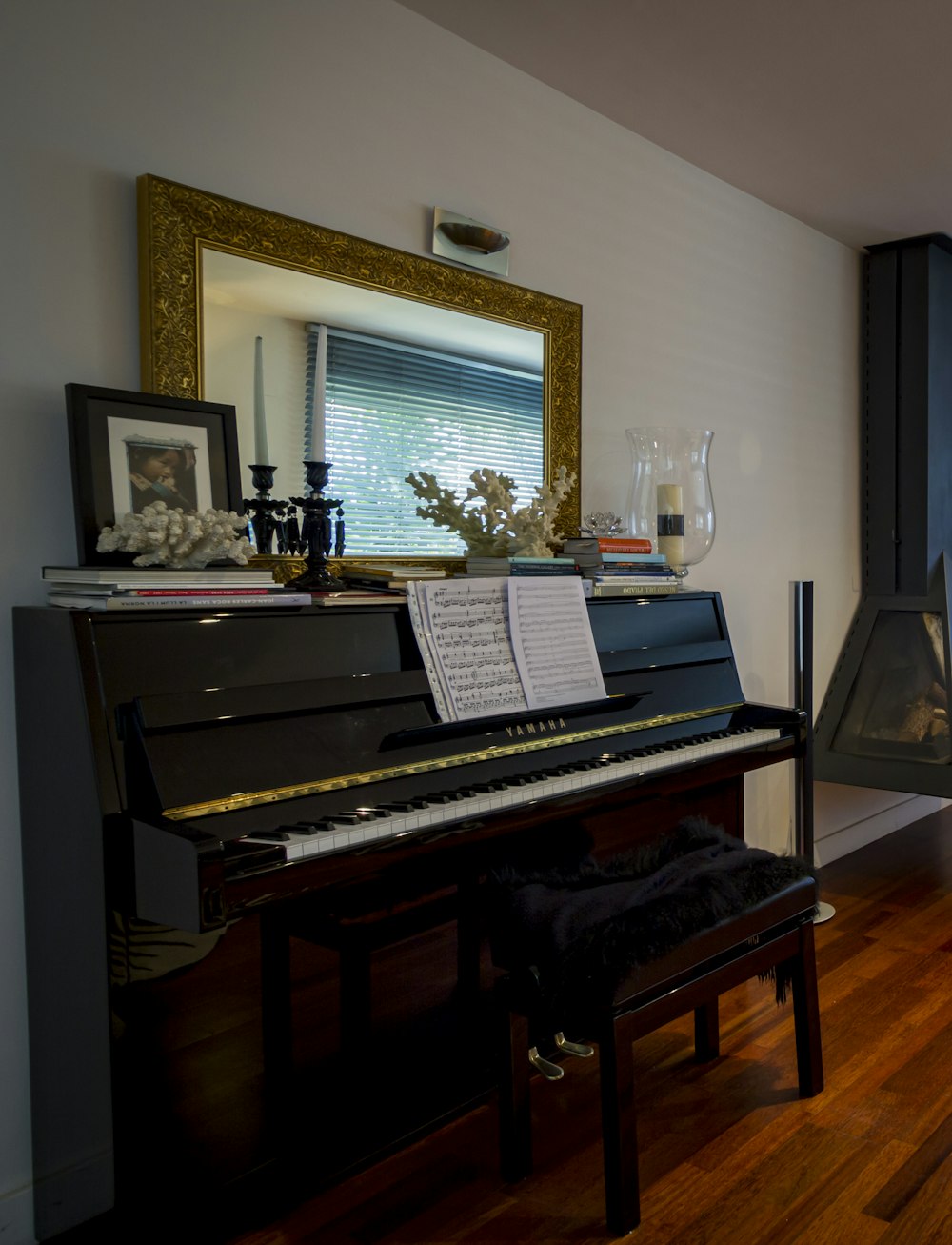 茶色の木製フレームの鏡の近くの黒いアップライトピアノ