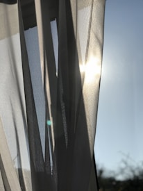 A close-up of pastel-colored curtains with cloud designs hanging in a sunny room.