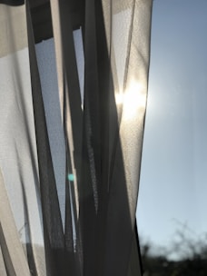 Bright, freshly cleaned curtains hanging by a sunny window.