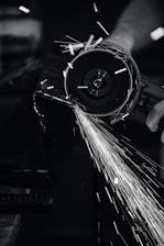 Close-up of a technician grinding a concrete floor, dust particles suspended in the air under industrial lighting.