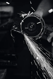 Close-up of a grinding machine smoothing a metal surface with sparks flying.