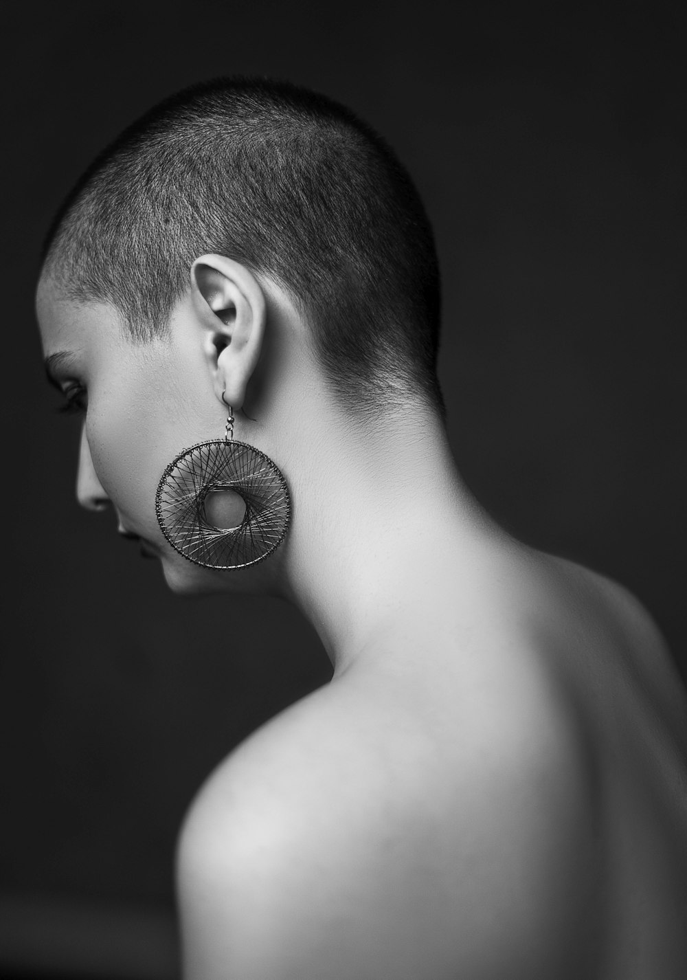 topless boy looking at round silver ornament