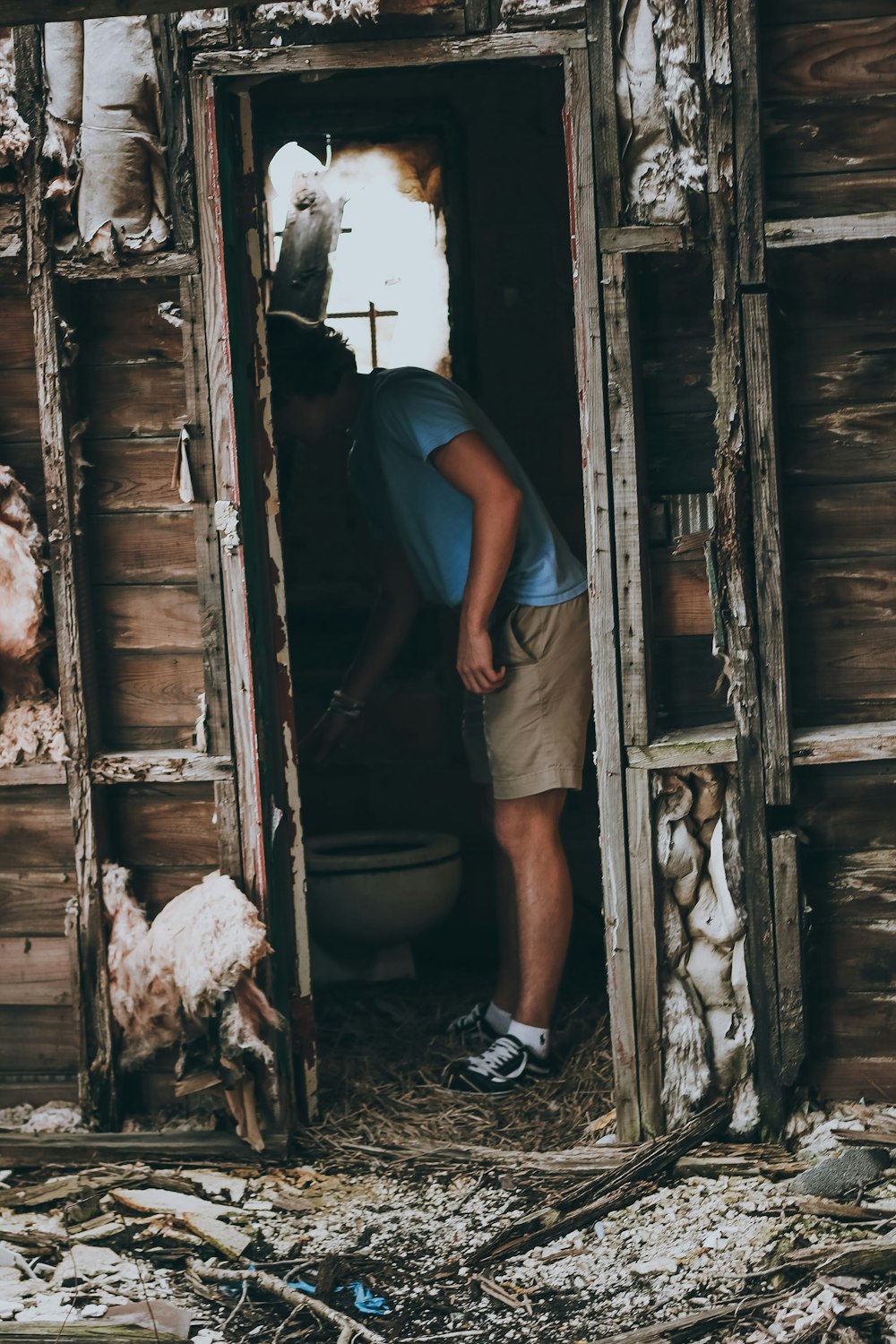 a man standing in the doorway of a dilapidated building