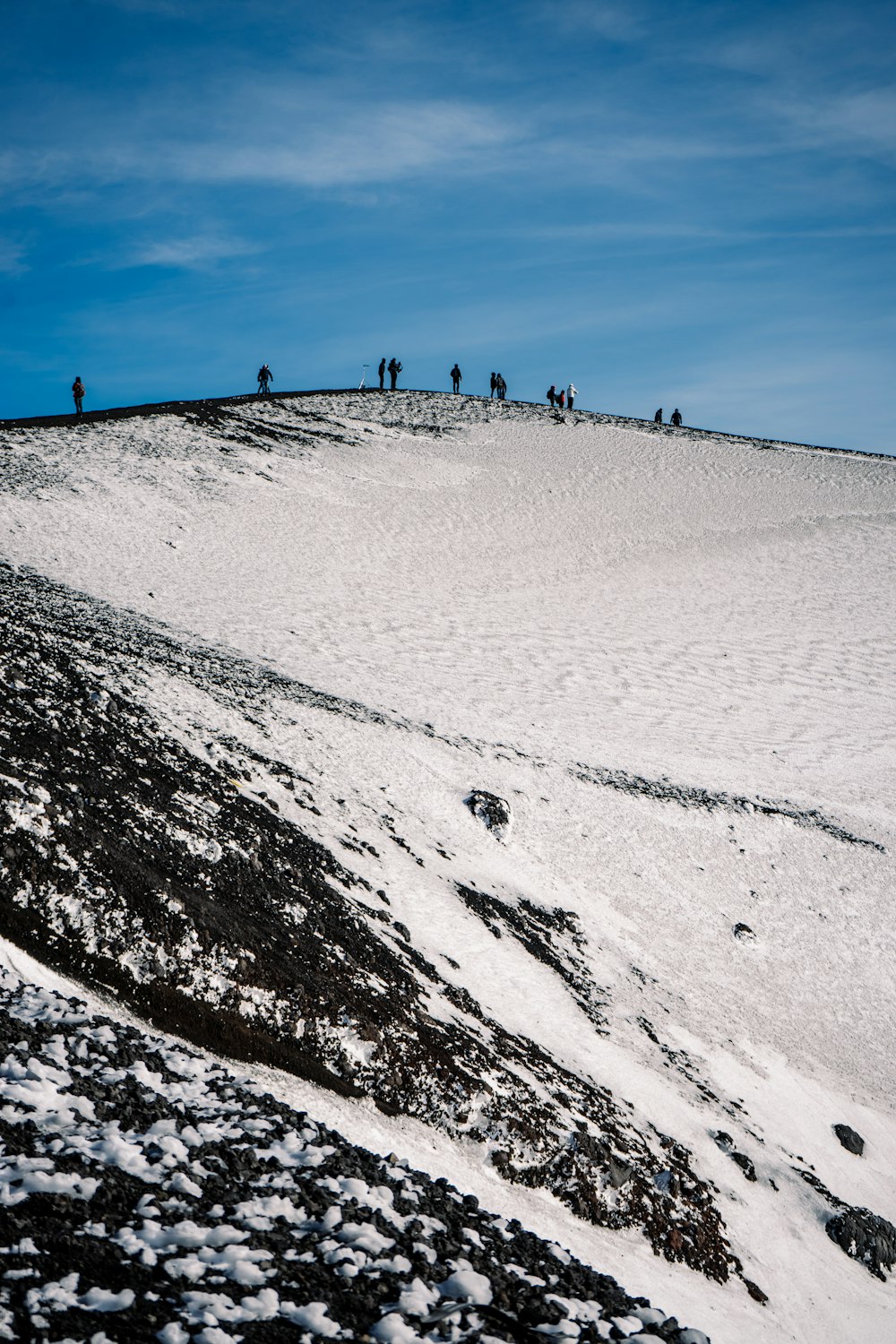 people walking on snow covered field under blue sky during daytime