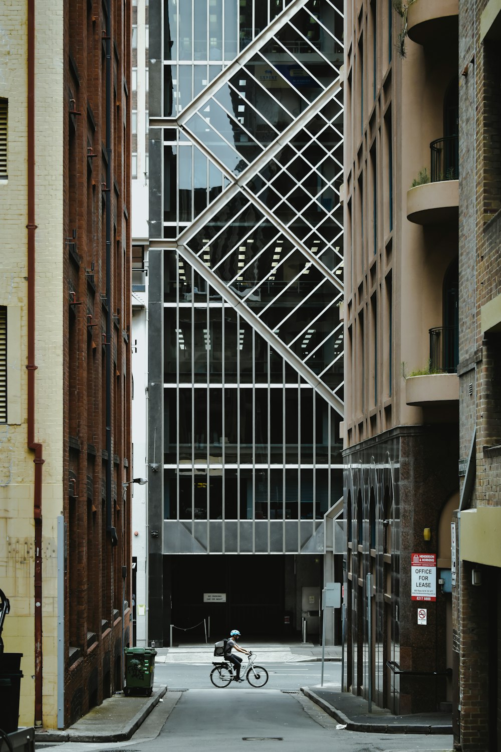 a person riding a bike down a street next to tall buildings