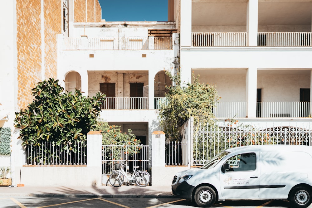 white and black car parked beside white metal fence during daytime