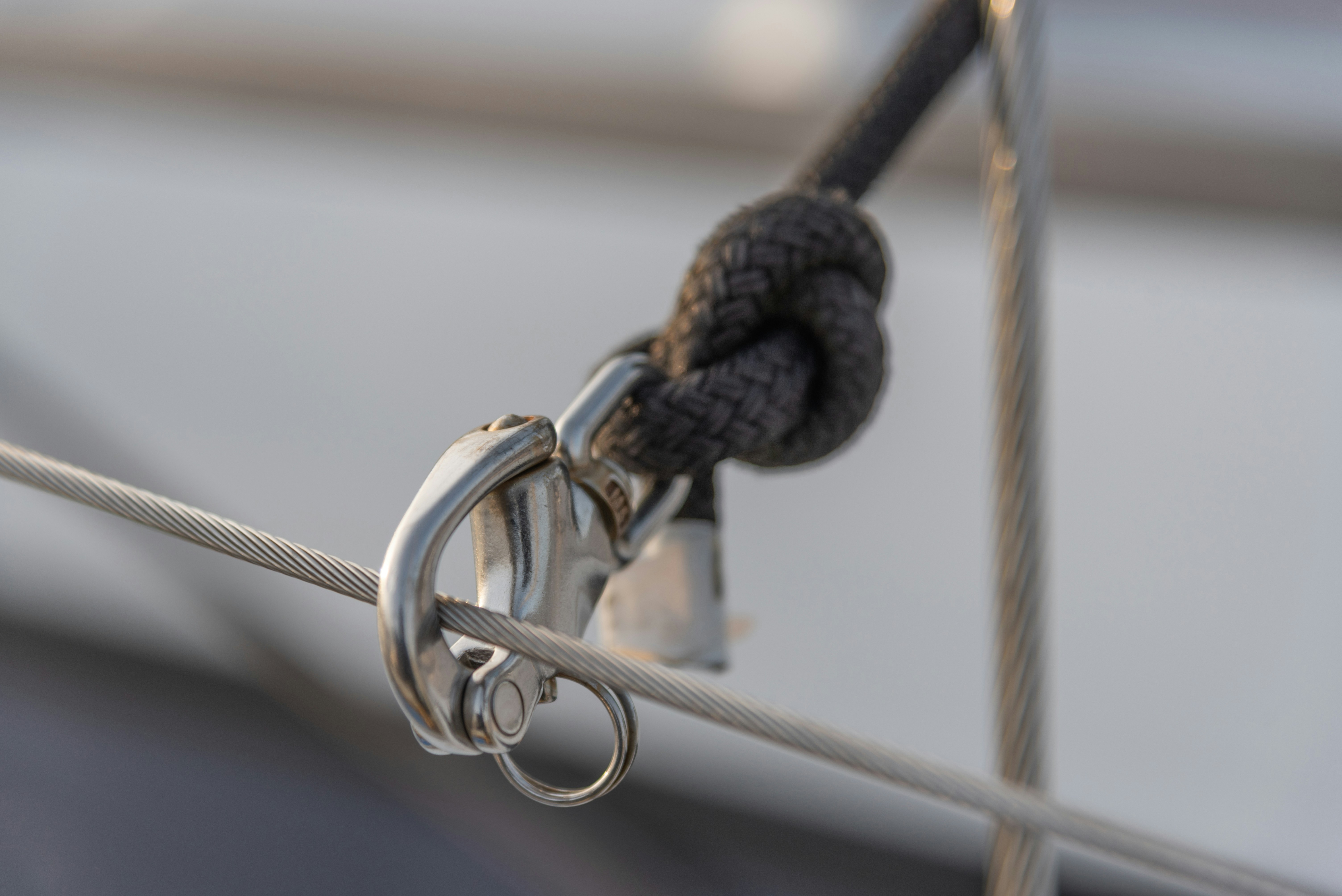 Stainless steel shackle connecting a braided rope to steel cables.