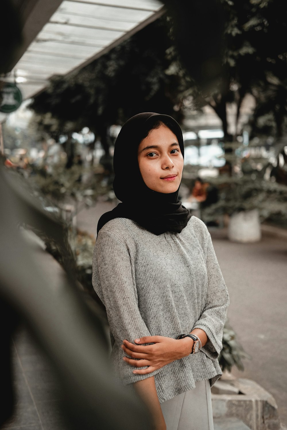 woman in gray sweater standing on road during daytime