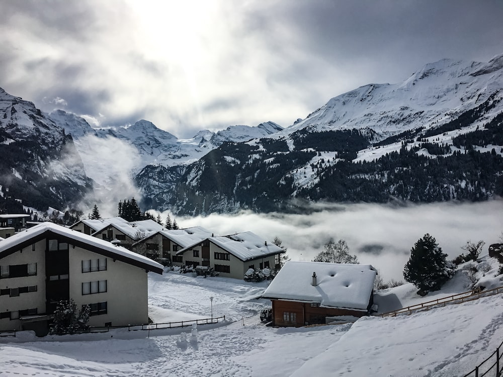 Braunes und weißes Haus auf schneebedecktem Boden in der Nähe schneebedeckter Berge tagsüber