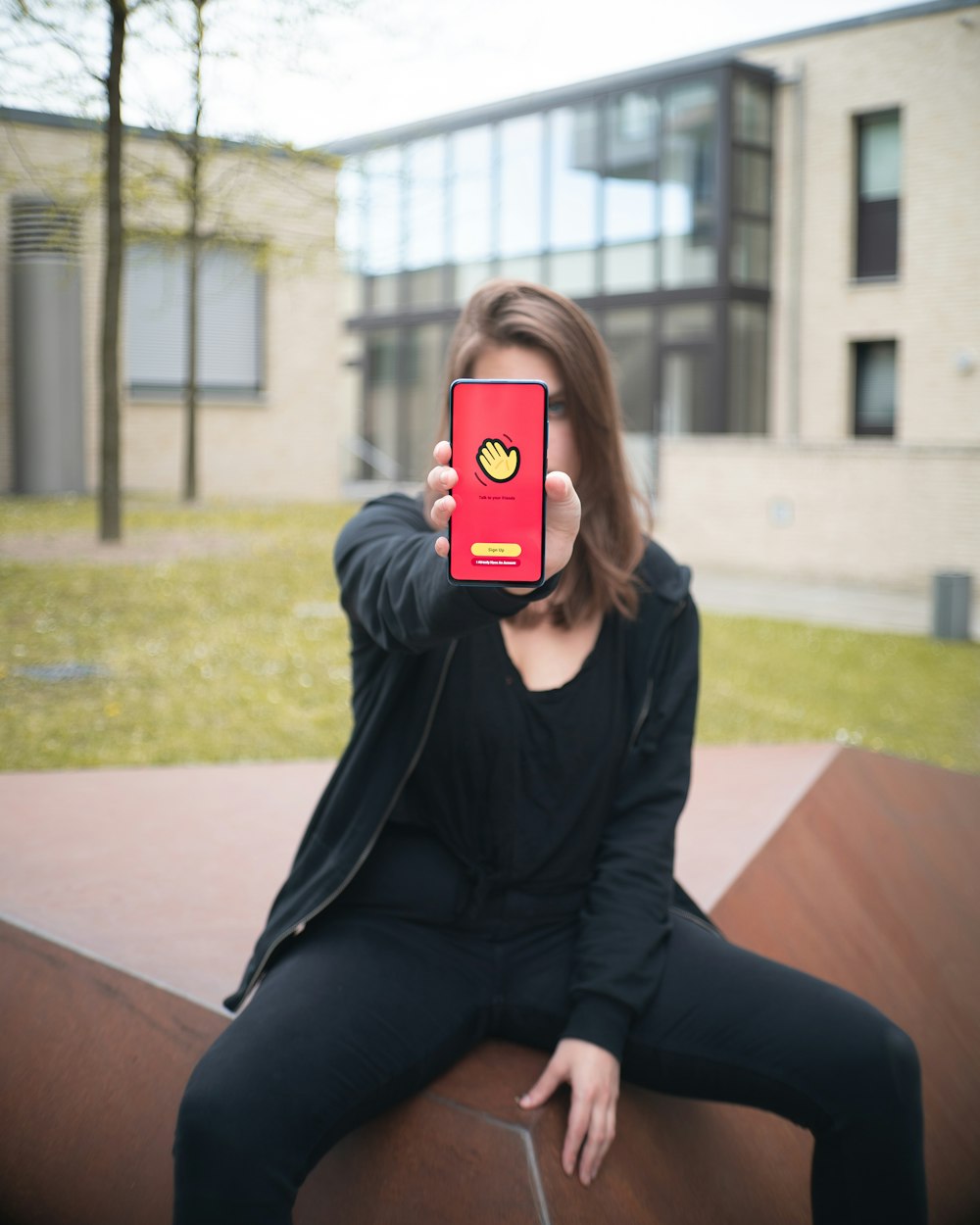 woman in black long sleeve shirt and black pants holding iphone