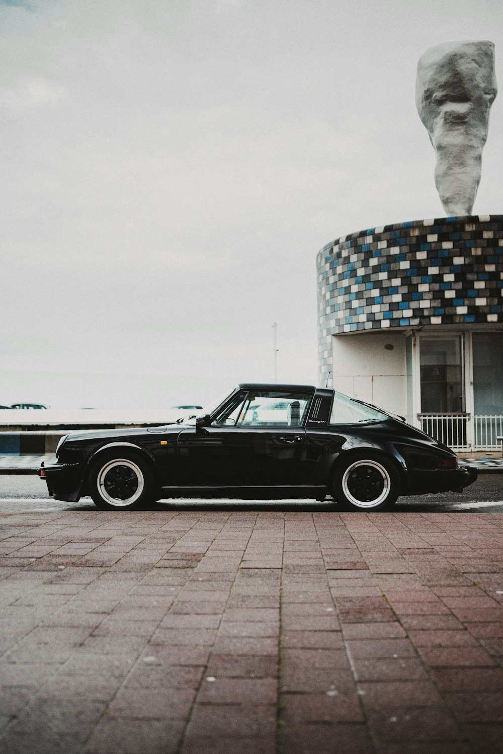 black coupe parked beside white concrete building during daytime