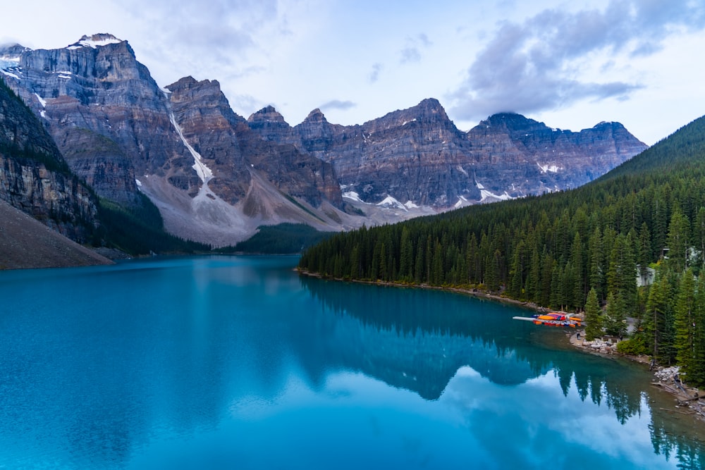 lake surrounded by green trees and mountains during daytime