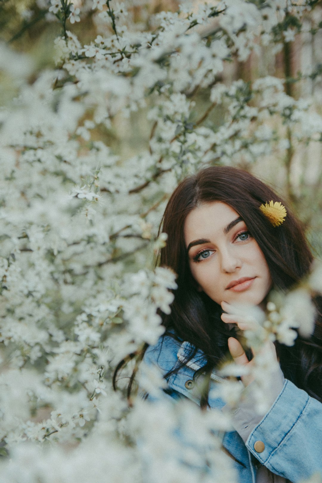 woman in blue denim jacket with white flower on her ear