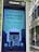 A public information screen installed by InLinkUK, featuring a COVID-19 safety message from the Mayor of London. The sign advises staying home to save lives, allowing only necessary outings for food, health reasons, exercise, or essential work. The illustration includes a house with individuals visible in the windows, surrounded by city buildings.