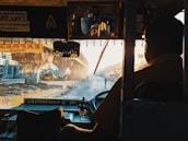 A friendly driver greeting a passenger with a sign at a busy transfer point.