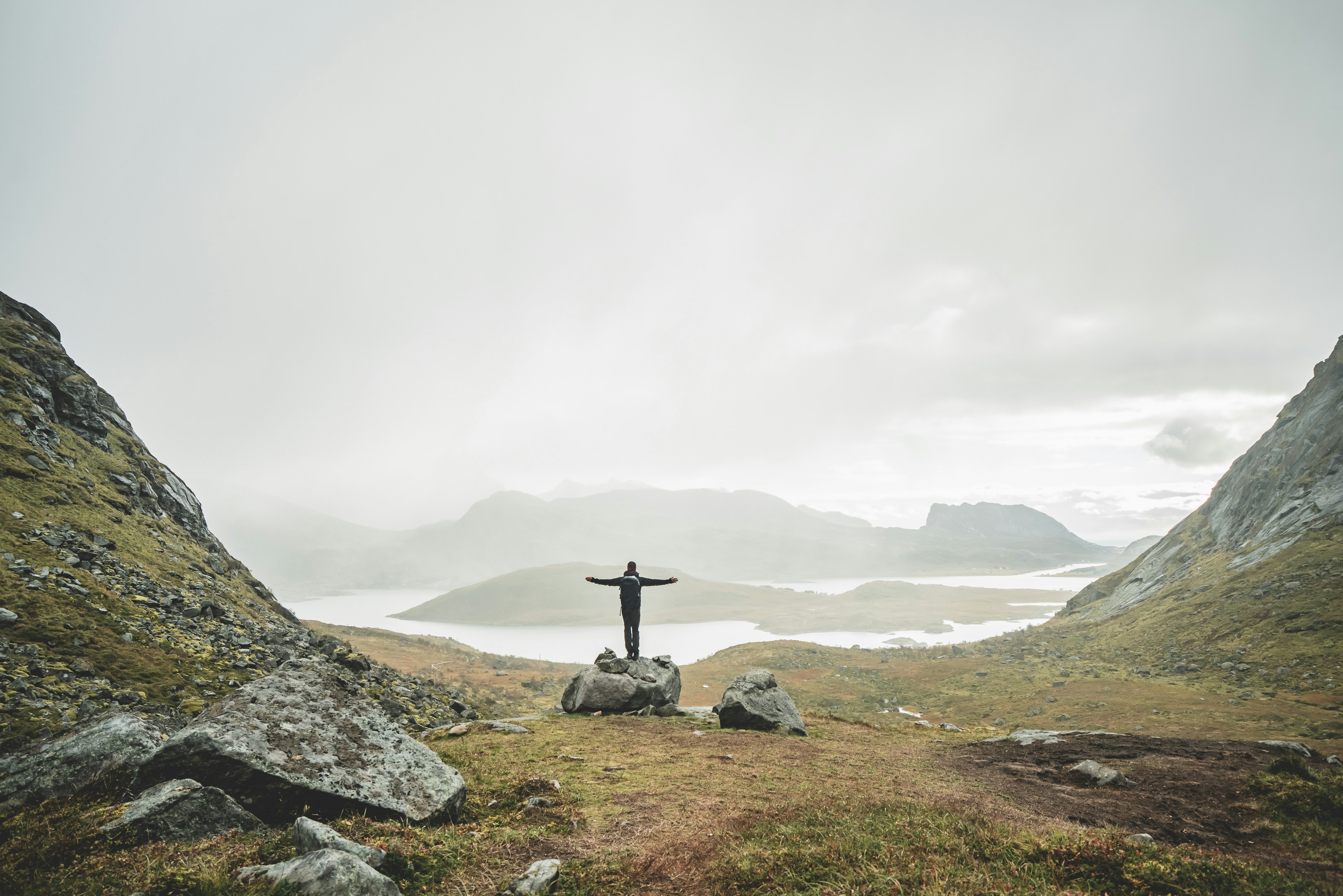 Person, die tagsüber auf grauem Felsen in der Nähe von Gewässern steht