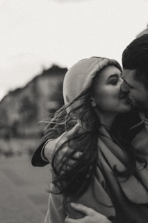 grayscale photo of man kissing womans forehead