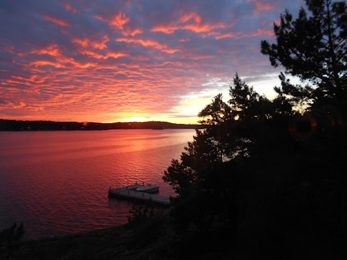 A vibrant sunset over a calm lake with a boat silhouette.