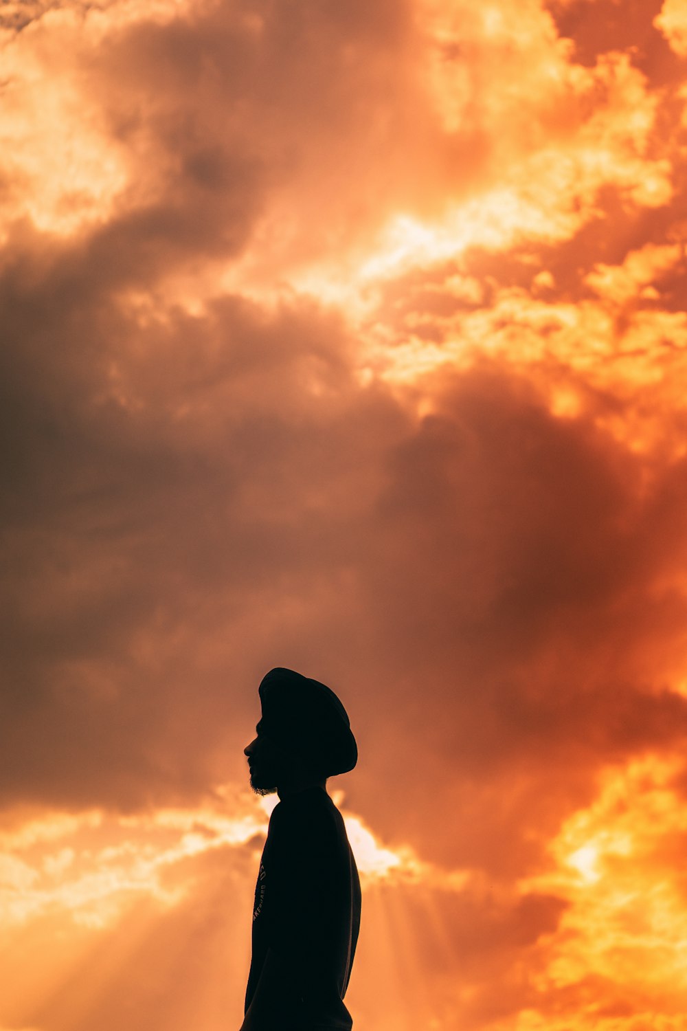 a silhouette of a person standing under a cloudy sky