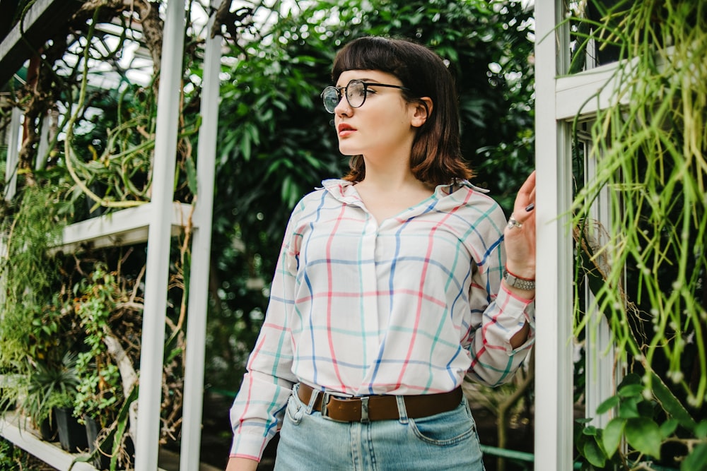 woman in red white and blue plaid dress shirt and blue denim jeans wearing black sunglasses