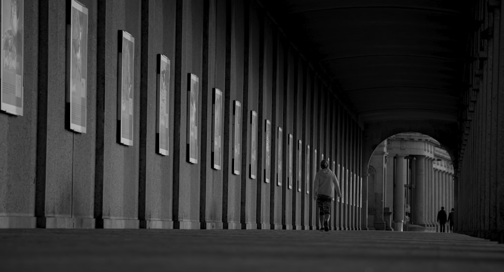 grayscale photo of person walking on hallway