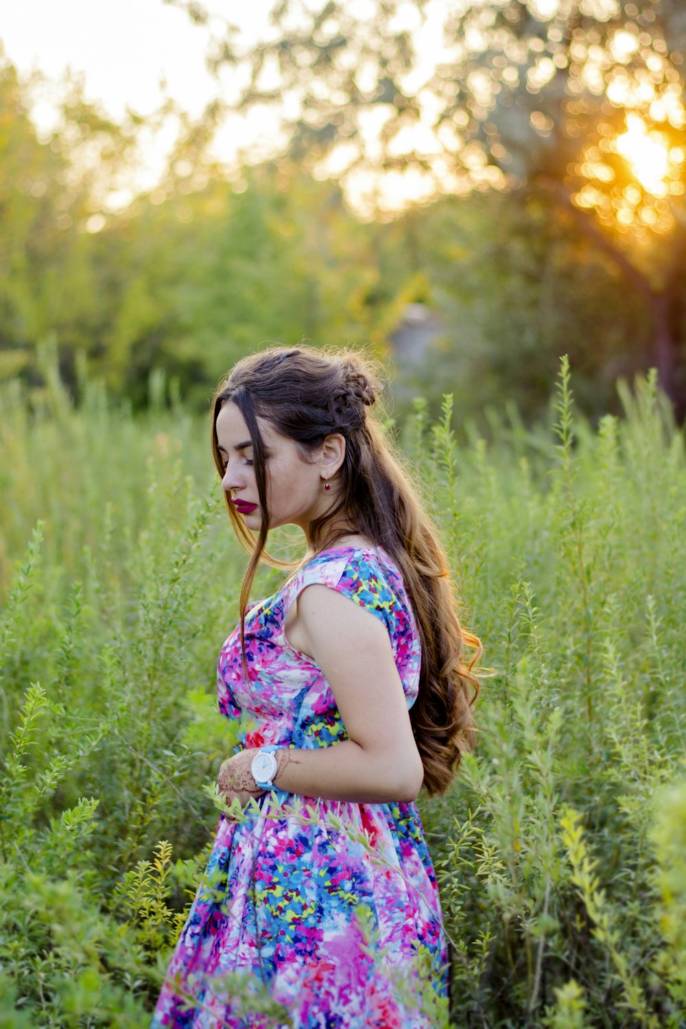 girl in white and pink floral tank top standing on green grass field during daytime