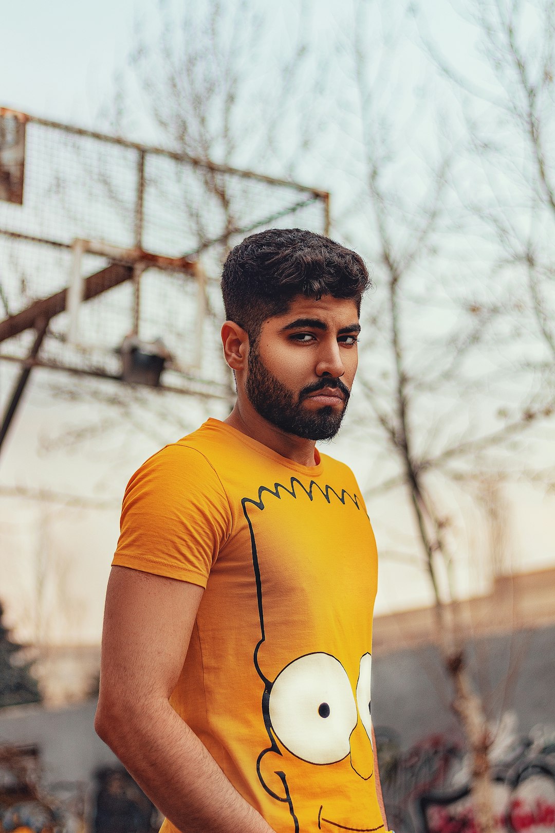 man in yellow crew neck t-shirt standing near bare trees during daytime