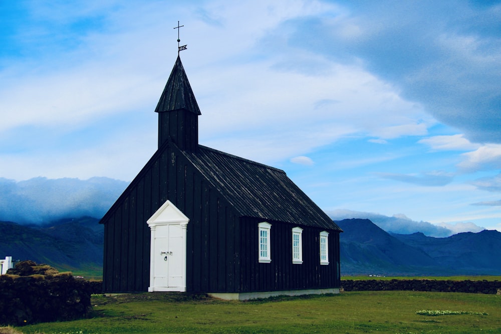 white and black church on green grass field under white clouds and blue sky during daytime