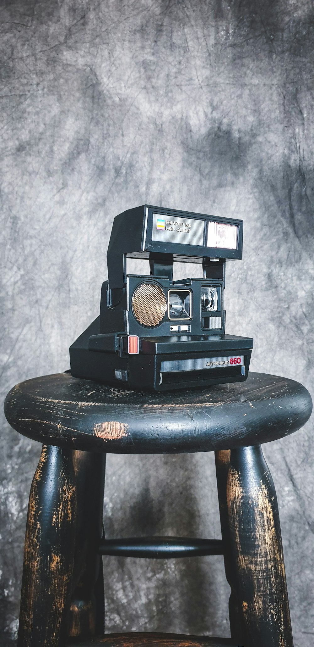 black and red polaroid camera on brown wooden seat