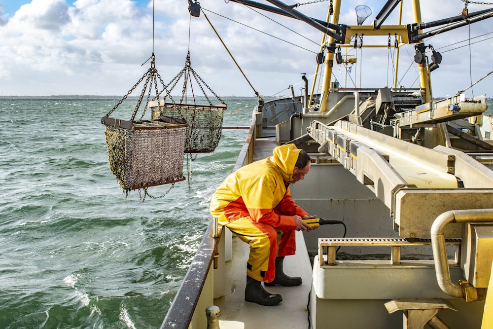 Mann in gelber Robe tagsüber auf weißem Boot