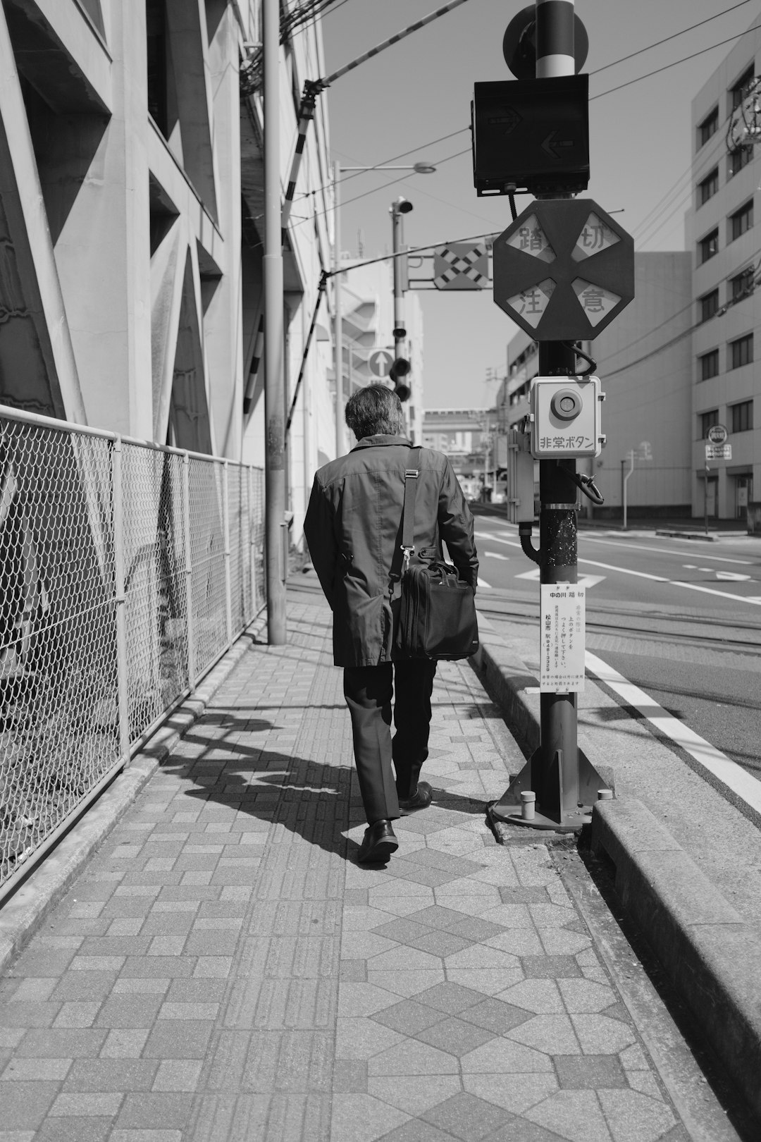 man in black jacket walking on sidewalk during daytime