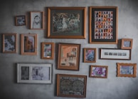 A collection of framed hand-painted glass artworks displayed on a rustic wooden wall